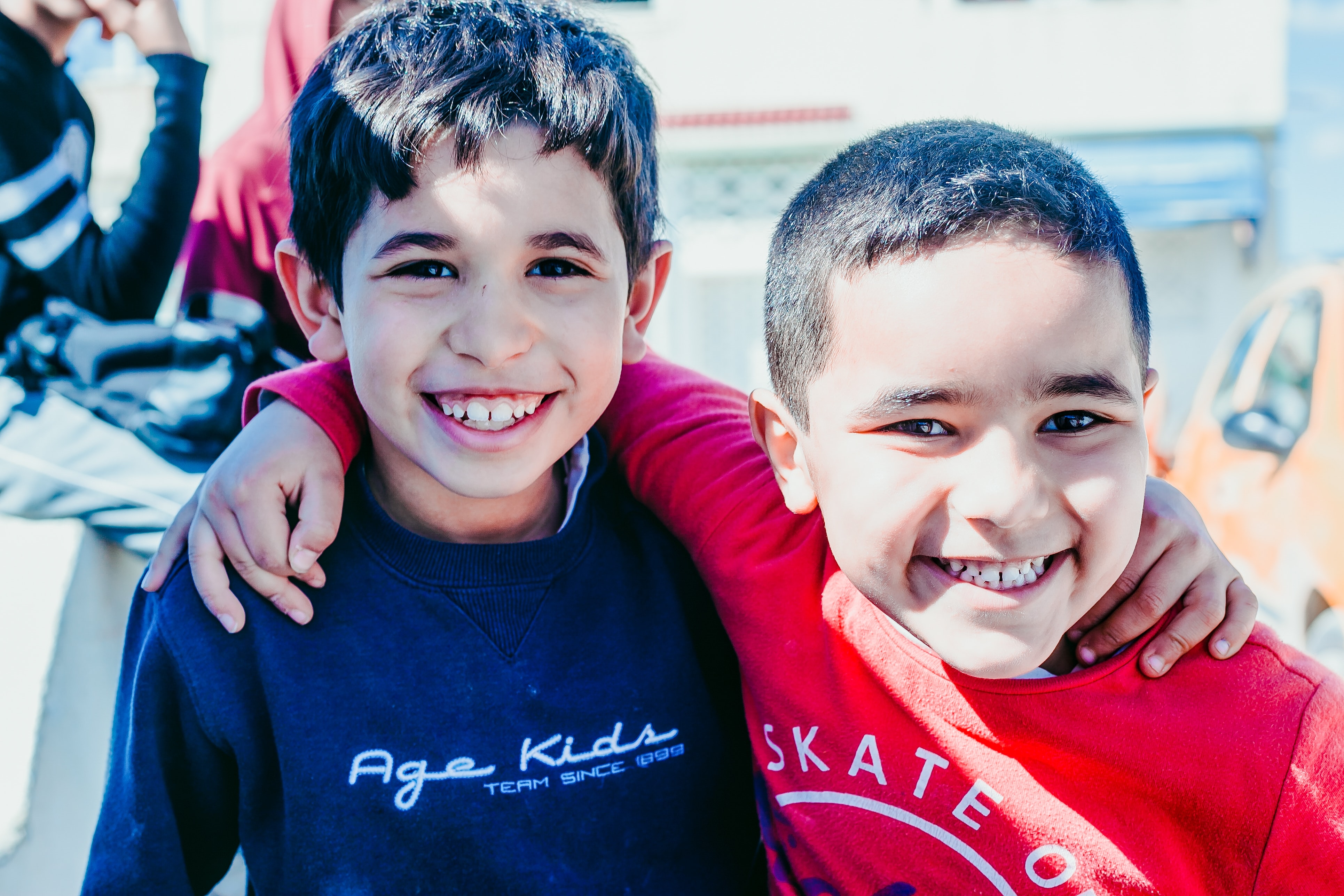 Two young boys smiling at the camera with arms around each other's shoulders